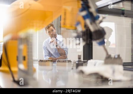 Businessman checking industrial robot in high tech company Stock Photo