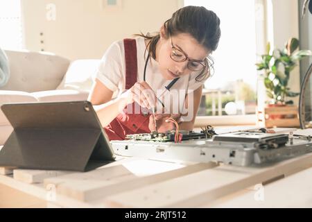 Young woman working on computer equipment at home next to tablet Stock Photo
