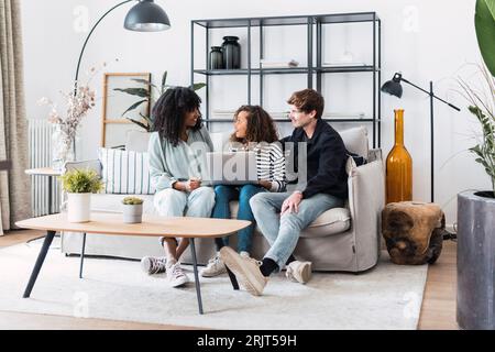 Happy family sitting on sofa with daughter using laptop Stock Photo