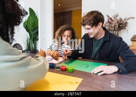 Family sitting at table drawing and painting together Stock Photo
