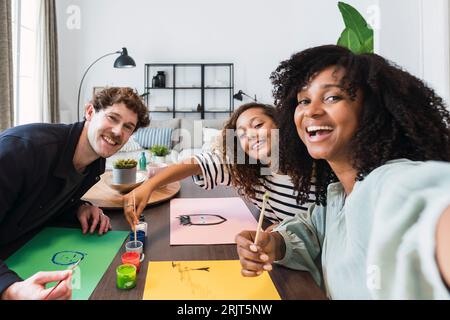 Family sitting at table drawing and painting together Stock Photo