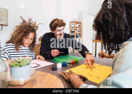 Family sitting at table drawing and painting together Stock Photo