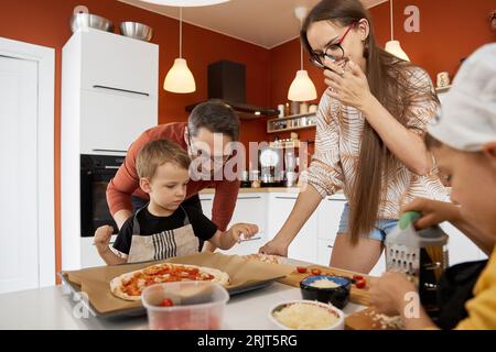 Happy family preparing pizza together at home Stock Photo