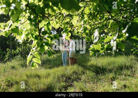 Couple discussing over map standing on grass in park at sunny day Stock Photo