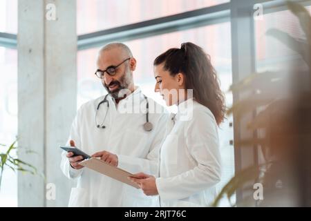 Mature doctor having discussion with colleague over tablet PC Stock Photo