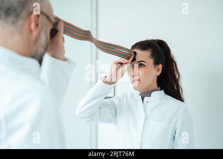 Scientists pretending to connect with multicolored computer cable in front of wall Stock Photo