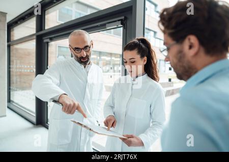 Doctors having discussion with patient over document in corridor Stock Photo