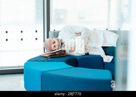 Tired doctor sleeping on sofa in hospital Stock Photo