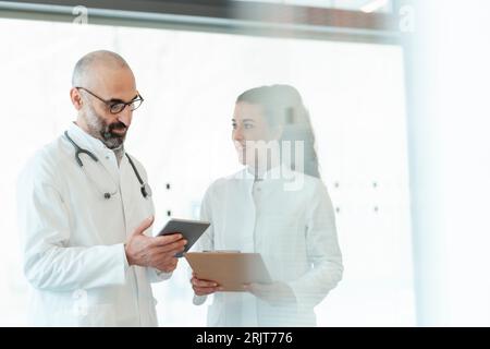 Happy doctor with colleague using tablet PC Stock Photo