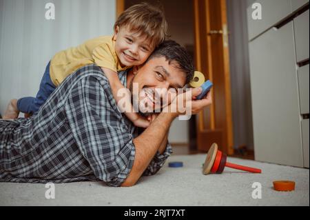 Smiling father and son playing with toys at home Stock Photo