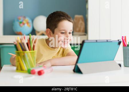 Smiling boy studying on tablet PC at home Stock Photo