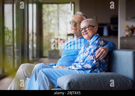 Senior man embracing woman on couch at home Stock Photo