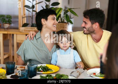 Smiling parents with son having lunch on dining table at home Stock Photo