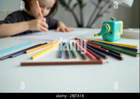 Boy drawing with colored pencils on table at home Stock Photo