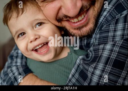 Smiling father embracing son at home Stock Photo