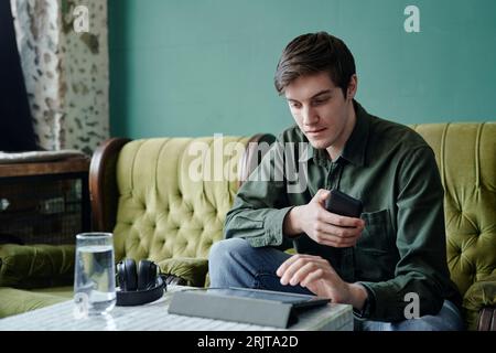 Young businessman sitting at table in modern cafe using tablet PC Stock Photo