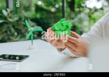 Hands of businessman with green puzzle cube at desk in office Stock Photo