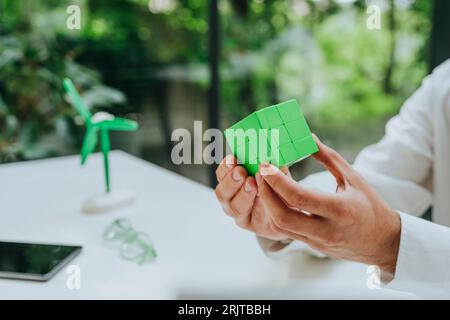 Hands of businessman with green puzzle cube at desk Stock Photo