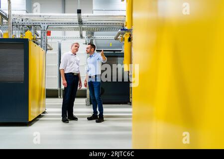 Two businessmen talking in factory Stock Photo