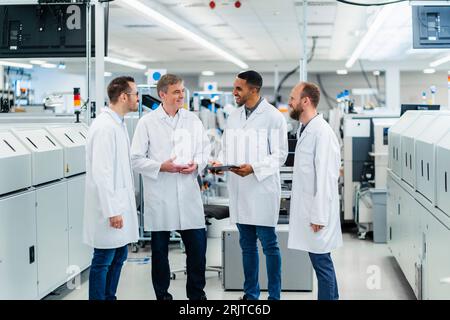 Technicians in lab coats having a meeting in electronics manufacture Stock Photo
