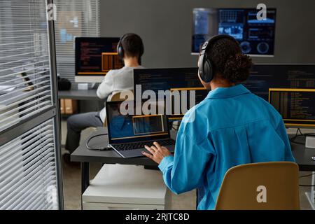 Young computer programmer with colleague working on desktop PC at desk Stock Photo