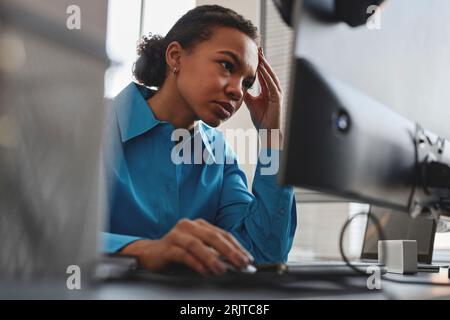 Stressed computer programmer working on desktop PC in office Stock Photo