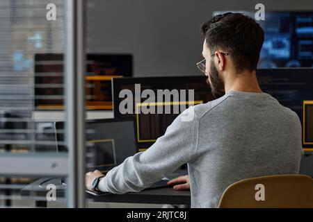 Computer programmer using laptop in front of desktop PCs Stock Photo