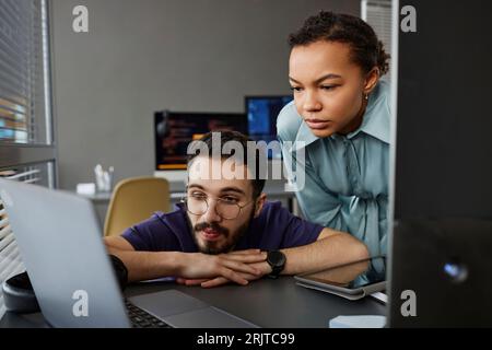 IT professionals working on laptop together at desk Stock Photo