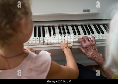 Grandmother and granddaughter playing piano at home Stock Photo