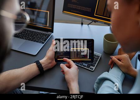 Computer programmers discussing together over tablet PC at desk Stock Photo