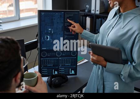 IT professional pointing on computer screen and having discussion with colleague Stock Photo