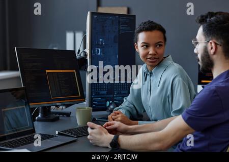 Smiling young computer programmers discussion together at desk in office Stock Photo
