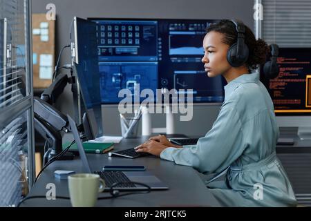 Young computer programmer wearing wireless headphones working on desktop PC Stock Photo