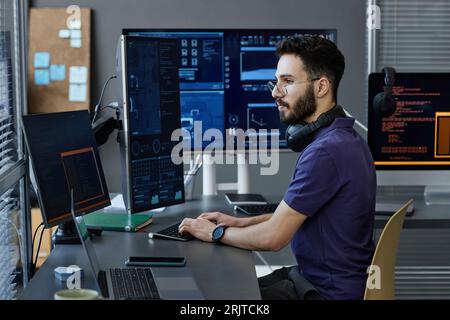 Young computer programmer with wireless headphones coding on desktop PC Stock Photo