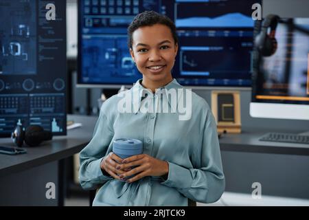 Happy young computer programmer sitting with coffee cup Stock Photo