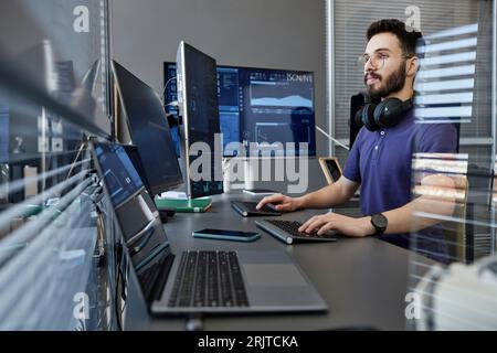 Young computer programmer with wireless headphones working on desktop PC Stock Photo