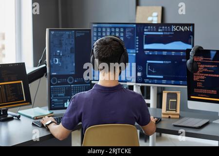 Young IT professional wearing wireless headphones working on computers Stock Photo