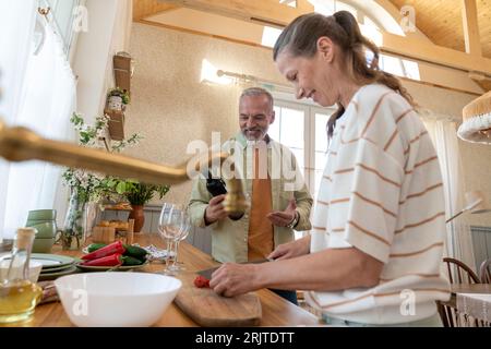 Couple assisting each other preparing food in kitchen at home Stock Photo