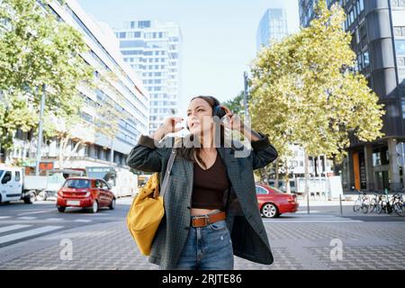 Contemplative woman listening to music at footpath Stock Photo