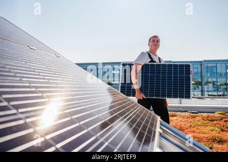 Craftsman carrying solar panel on the roof of a company building Stock Photo