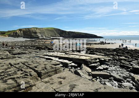 Eye Level view across Dunraven Bay showing rock slabs, Witches Nose, the Beach, the Sea and beach people  - in the Glamorgan Heritage Coast Area Stock Photo