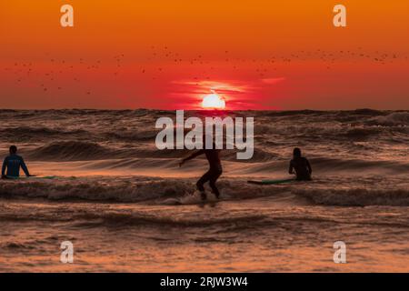 Surfers ply the wind-whipped waves as the sun sets over Lake Huron on a gorgeous summer evening Stock Photo