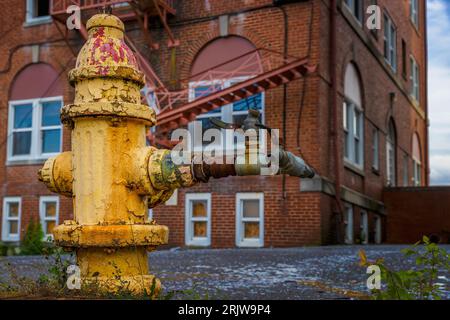 Close up of a fire hydrant in front of an abandoned brick building. Stock Photo