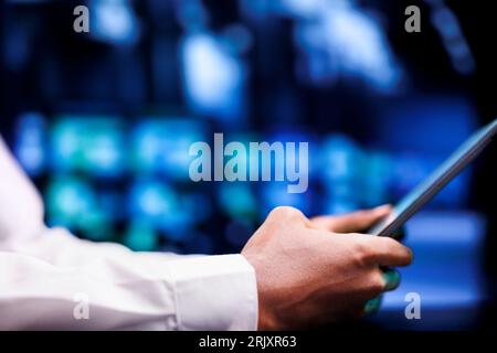 Proficient worker resolving performance related issues in data center mainframes. Engineer utilizing mock up tablet to identify operational problems causing blade servers slowdown Stock Photo
