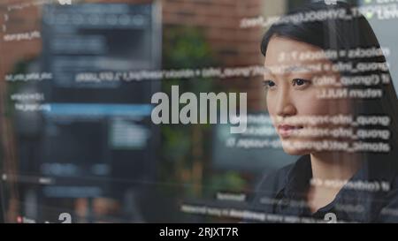 System administrator being helped by AR hologram to visualize script, writing code on computer screen while in office using programming language. Expert fixing errors during server maintenance Stock Photo