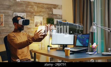 Freelancer in home office wearing VR goggles using AR hologram to visualize end result. Specialist working on machinery construction using cad engineering software, developing turbine components Stock Photo