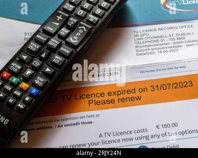 Irish orange TV licence reminder with television remote control. Stock Photo