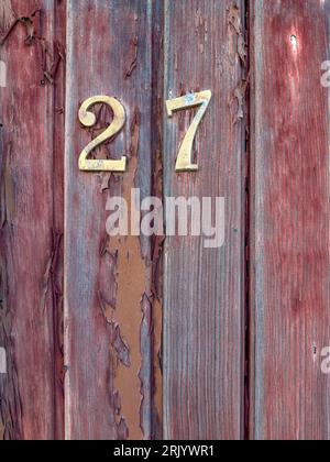 Number 27 on red painted old wooden wall. Red background. Stock Photo