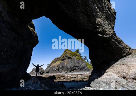 Hikers can walk under a big arch at low tide at Point of Arches, Olympic National Park, Washington State, USA Stock Photo