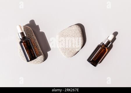 Natural cosmetics in two bottles with a pipette lying on oval flat gray stones. A copy of the space. Design branding. empty packaging Stock Photo